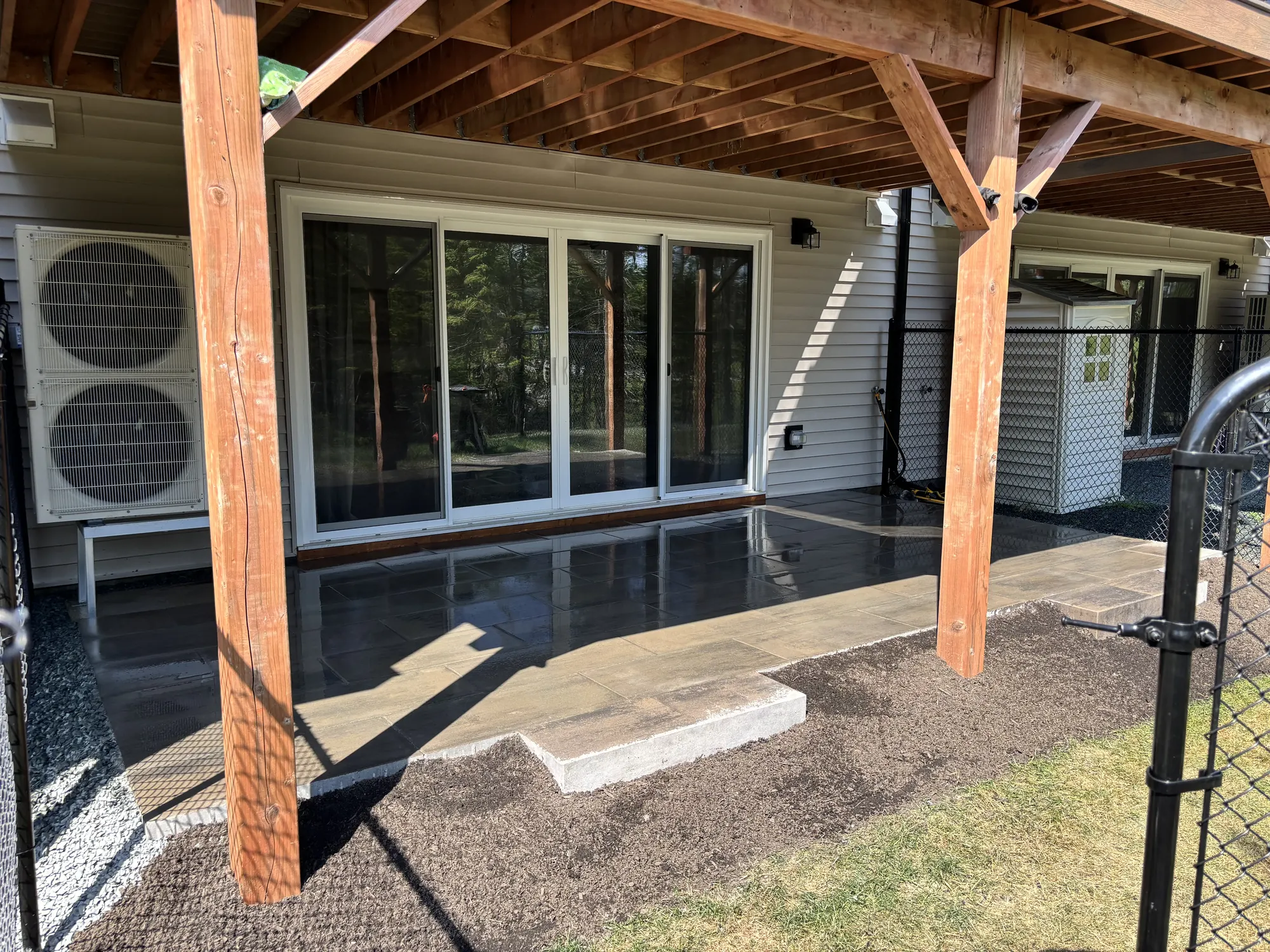 Stone patio being laid beneath a covered deck with large sliding glass doors, a hardscaping project in Halifax, Nova Scotia