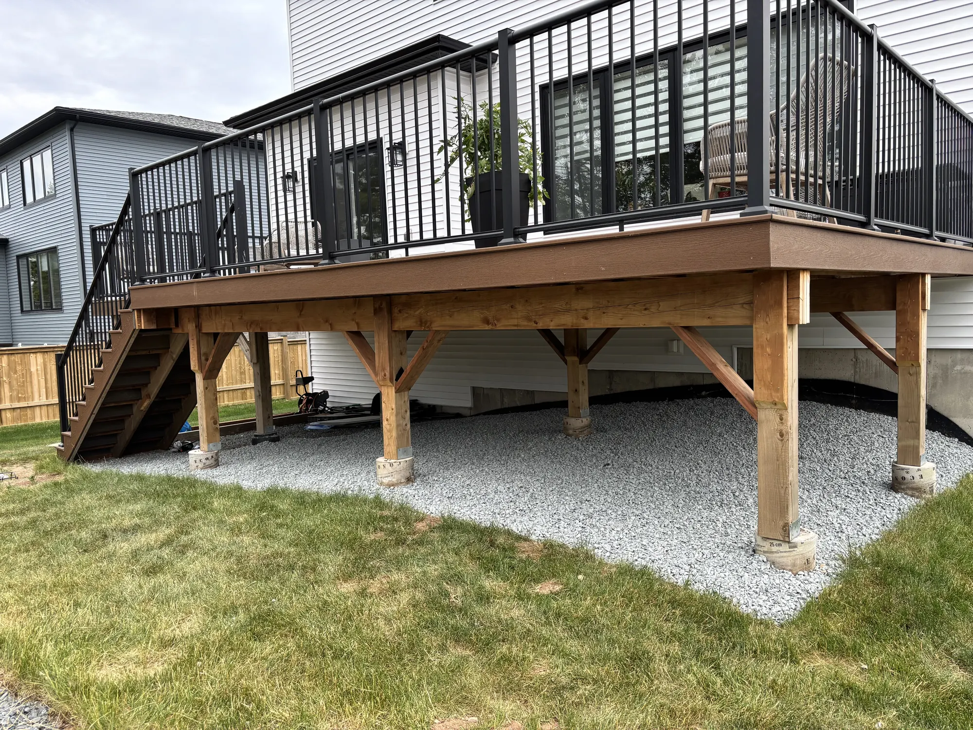 Elevated cedar deck with black railings over a clean gravel base and fresh lawn
