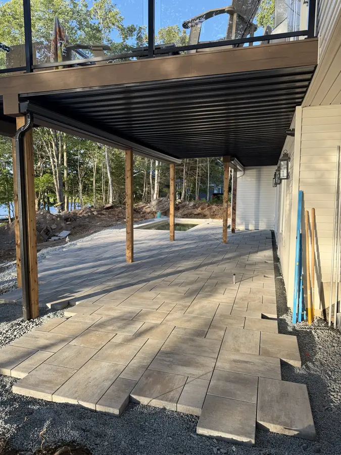 Large-format paver patio under an elevated deck with a clean gravel edge — hardscaping project in Halifax, Nova Scotia