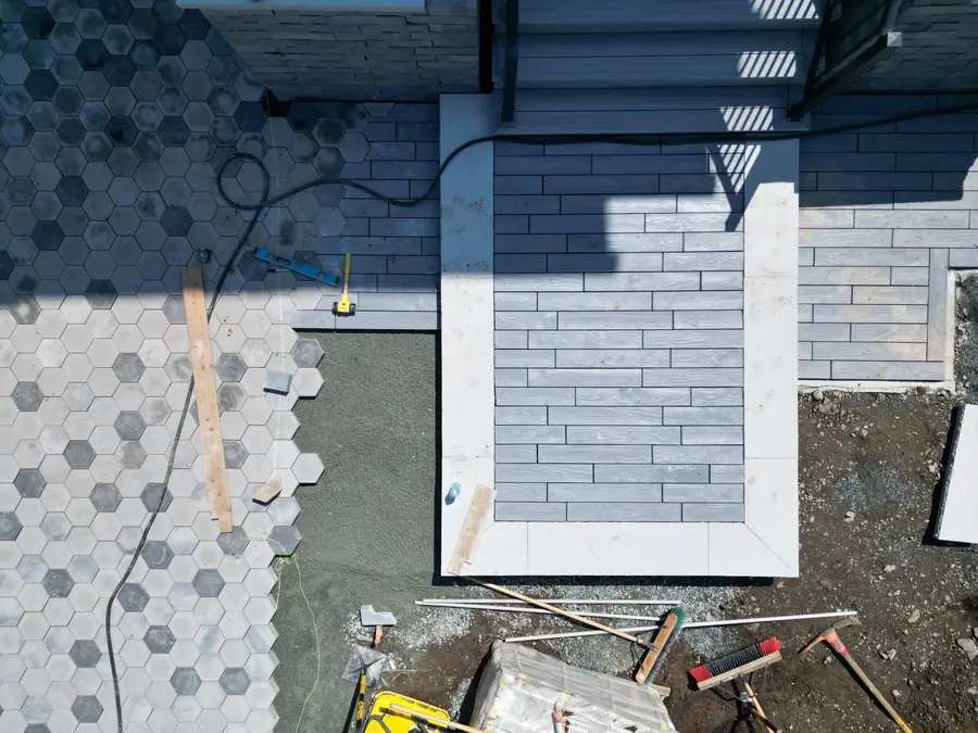 Close aerial view of hexagon pavers meeting a slab entrance landing with a string line and tools — hardscaping project in Halifax, Nova Scotia