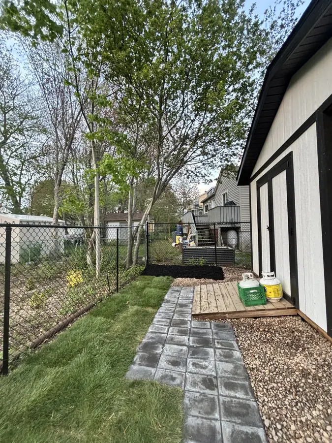 Interlocking paver walkway with a gravel border running along a white garage and fresh lawn — hardscaping project in Halifax, Nova Scotia