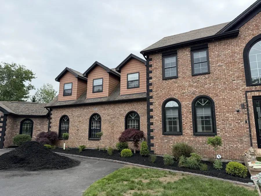 Brick home with freshly mulched beds, shrubs and a Japanese maple along the front — landscaping project in Halifax, Nova Scotia